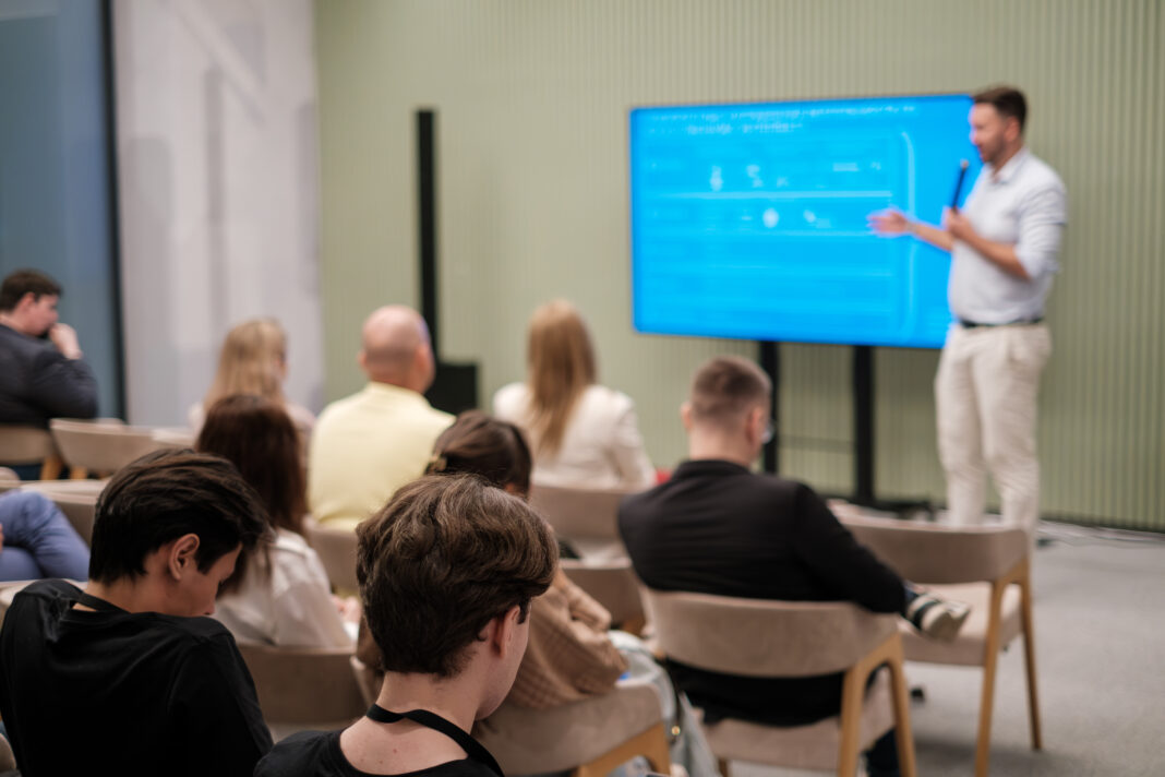 Speaker addressing diverse audience during educational seminar in modern conference space
